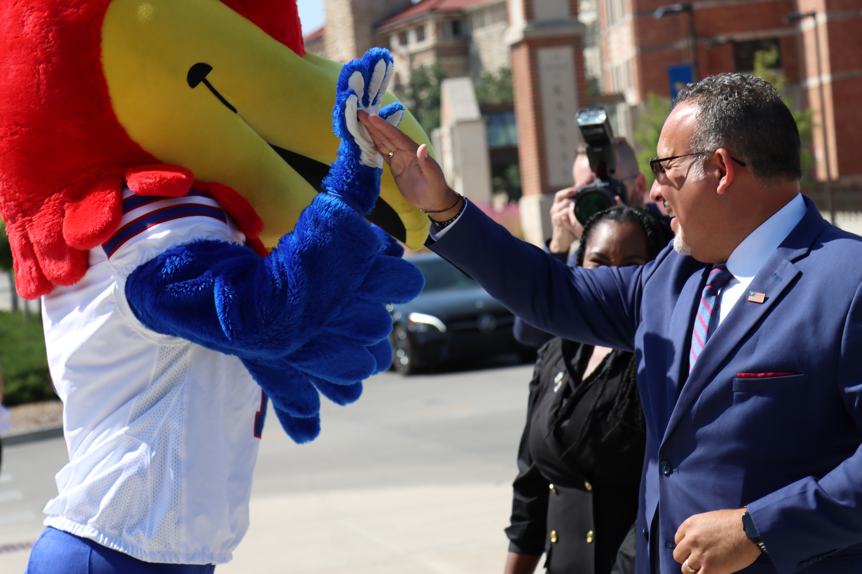 U.S Secretary of Education Miguel Cardona high-fives KU mascot Big Jay as he arrives for his University of Kansas visit. 