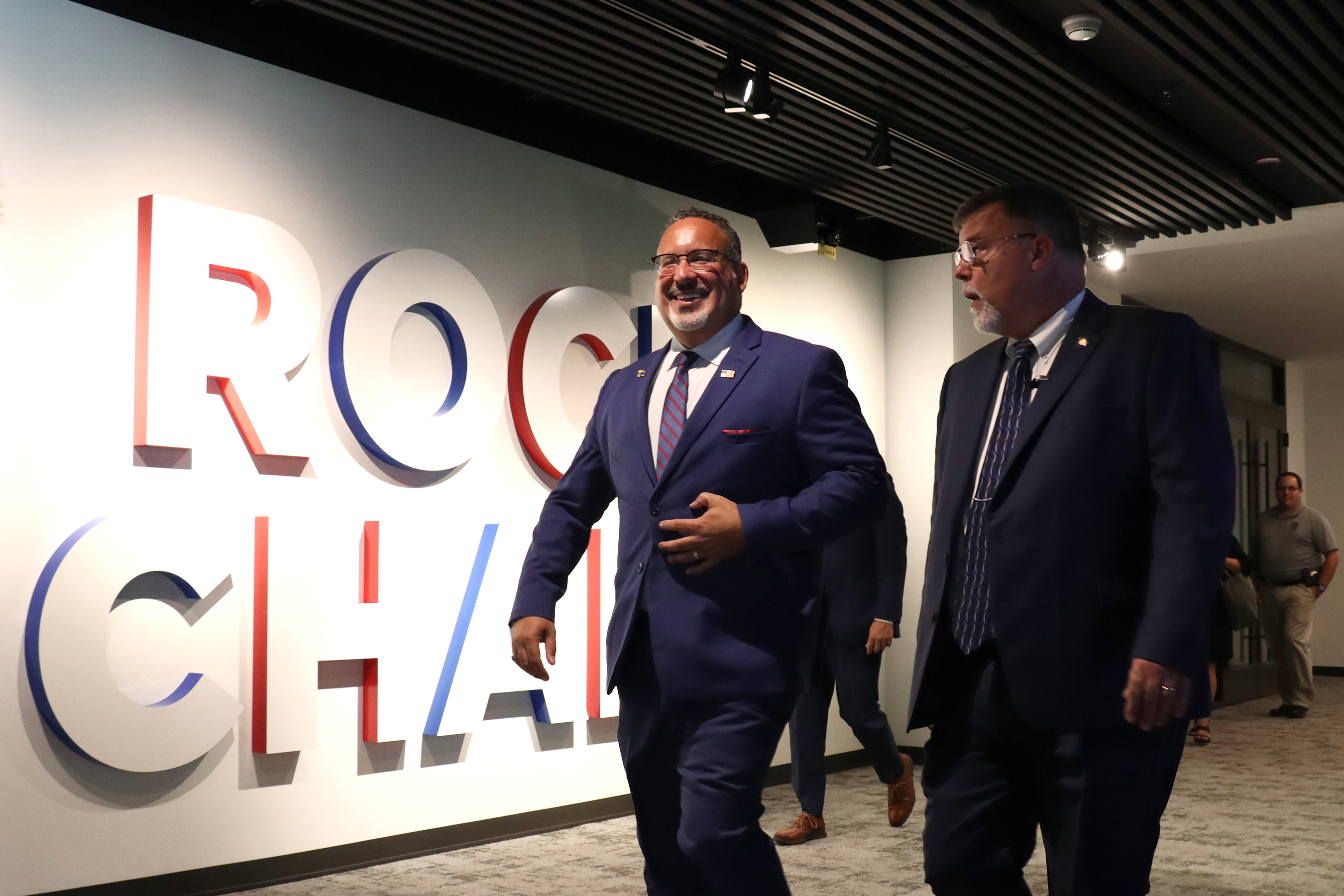 U.S. Secretary of Education Miguel Cardona walks past a wall with “Rock Chalk” written on it at the Jayhawk Welcome Center. 