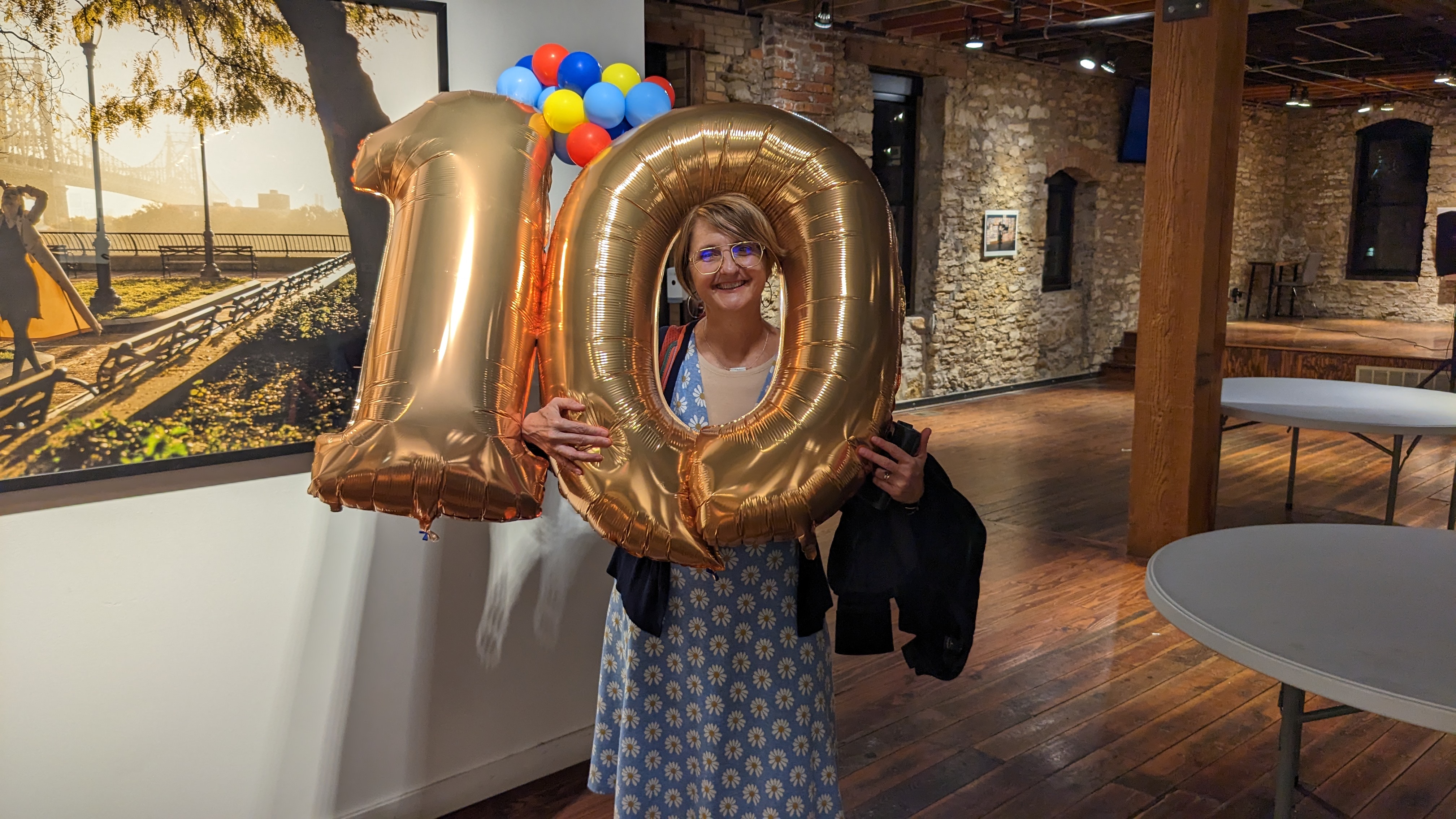 CPPR Director Jackie Counts holds a large 10-shaped balloon at the Cider Gallery in Lawrence, Kansas. 2013 is also the ten year anniversary of Center for Public Partnerships & Research.