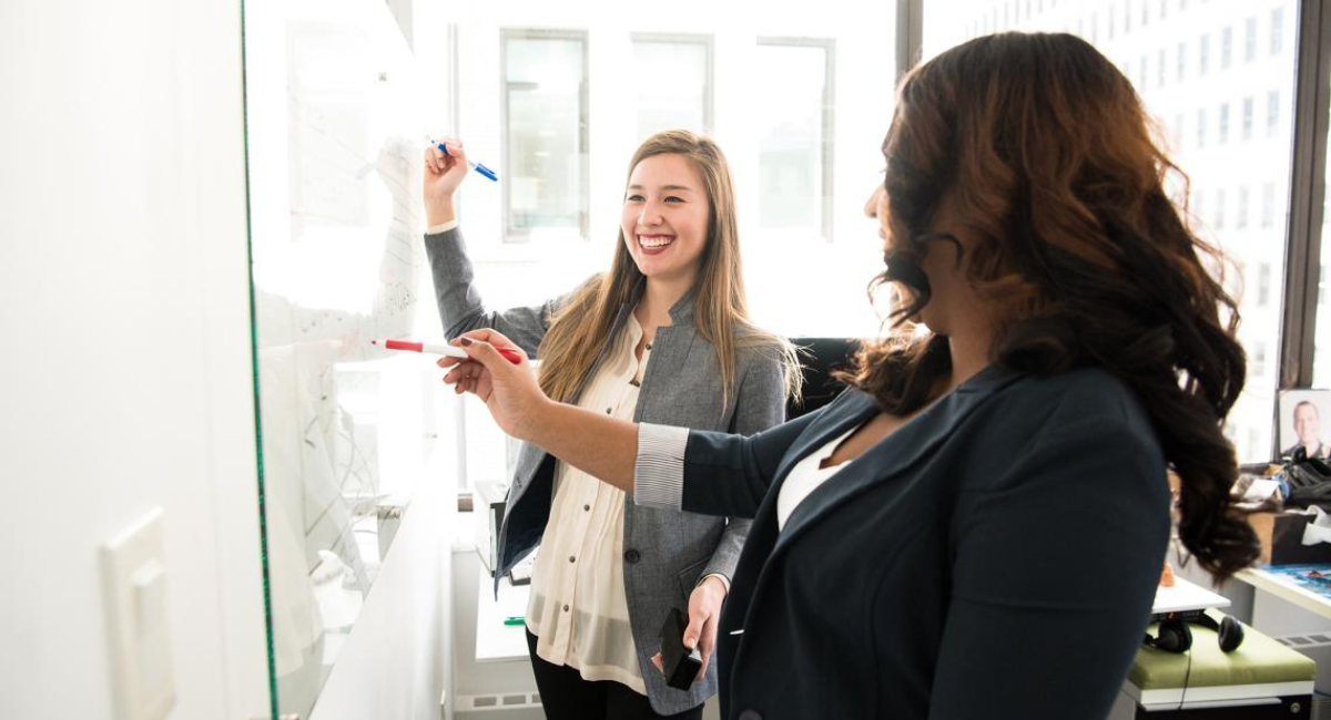 Two women at a whiteboard. 